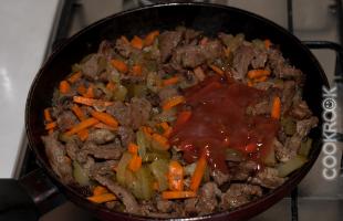 жареное мясо с луком, морковью, соленым огурцом и томатным соусом